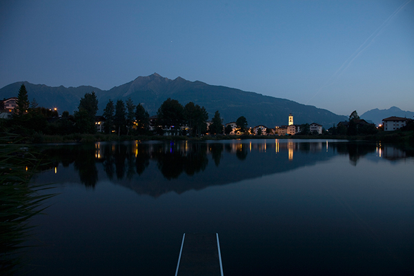 Abendstimmung am Laaxersee. Im Hintergrund die Pfarrkirche von Laax